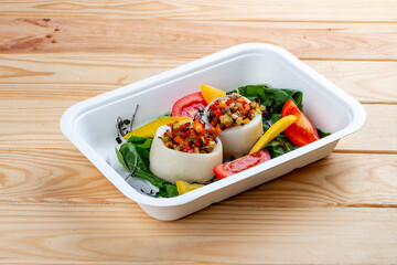 Squid stuffed with vegetables. Healthy diet. Takeaway food.  On a wooden background.
