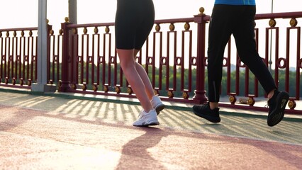 Man and woman legs jogging outdoor. Rear of people run on the bridge. Male and female legs running...