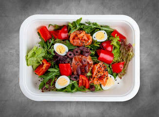 Salad with lightly salted salmon and bell pepper. Healthy food. Takeaway food. Top view, on a gray background.
