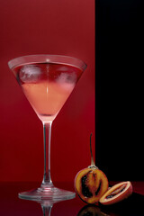 Martini glass with a cut tamarillo piece with a red and black background