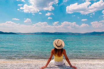 Woman admiring the magnificent view of Salda Lake. The woman sits against the view and poses with...