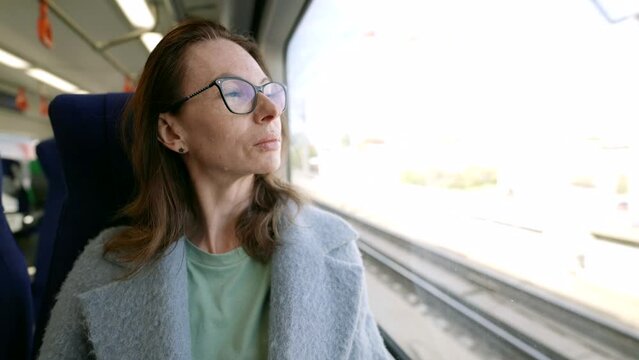 A ride on public transport becomes a moment of exceptional grace thanks to the portrait of a pretty middle-aged woman in elegant glasses.