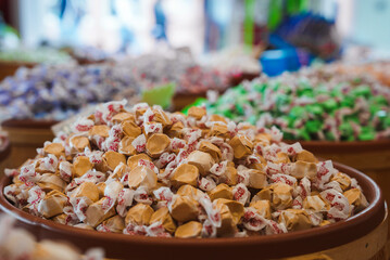 Close up view of wrapped candies in a market setting. Bowl of white and red candies in focus with...