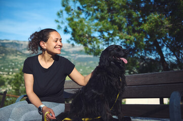 Happy woman and her cocker spaniel god looking way, sitting on the bench against mountains nature background. Woman walking pet in the nature