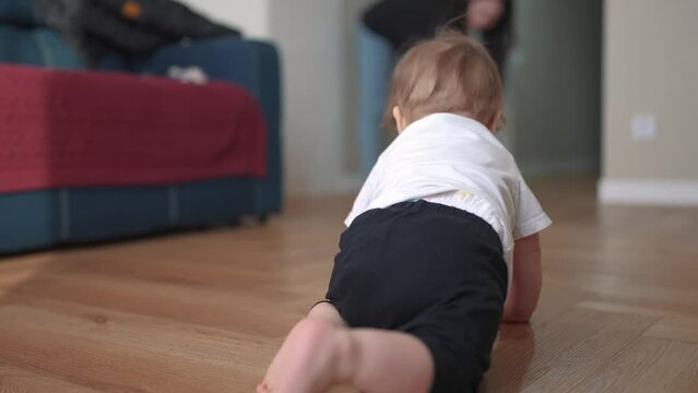 newborn baby crawls. happy family a kindergarten concept. First steps, crawling baby, view from the back. baby learns to crawl to explore the world lifestyle of dreams. the first steps creep up