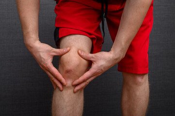 Sportowiec trzyma się za bolące kolano