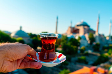 A man drinks Turkish tea opposite the Hagia Sophia Mosque. The man drinks his tea while admiring...