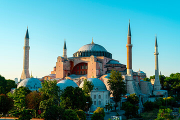 Hagia Sophia Mosque in Istanbul is a place of worship for Muslims. The photo of the building, which is surrounded by green trees, was taken on a sunny day.