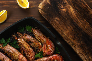 Fried shrimps on grill pan with fresh herbs and lemon slice. Seafood background.