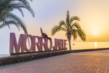 Morro Jable resort signage with palm letters outdoors on the coast on Fuerteventura island at sunset.