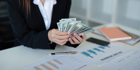 Businesswoman or financial bookkeeper holding bundle of money dollar for payment salary and income. entrepreneur counting money cash count salary profit finance at office