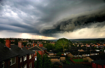 Dramatic storm clouds rolling in over a small tow with red brick houses. Yorkshire UK