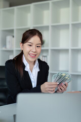 Businesswoman or financial bookkeeper holding bundle of money dollar for payment salary and income. entrepreneur counting money cash count salary profit finance at office