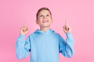 Photo of cute little schoolkid look direct fingers up empty space proposition isolated on pink...