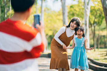 An Asian family of three heads to the park for a picnic, indulging in games and blowing bubbles together. 