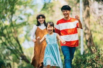 An Asian family of three heads to the park for a picnic, indulging in games and blowing bubbles together. 