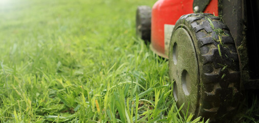 Lawnmover on on a grassy grass. An old red lawn mower mowing lush green grass