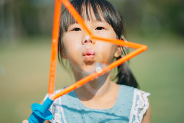 An Asian family of three heads to the park for a picnic, indulging in games and blowing bubbles together. 