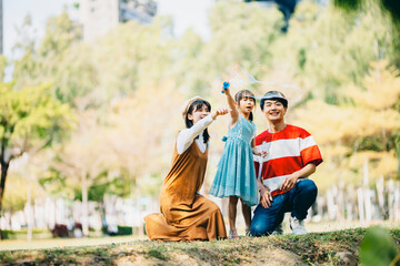 An Asian family of three heads to the park for a picnic, indulging in games and blowing bubbles together. 