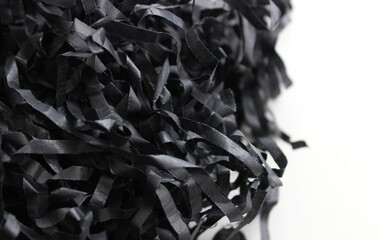 Intertwined strips of crumpled black wrapping paper isolated on white. Paper shavings for...