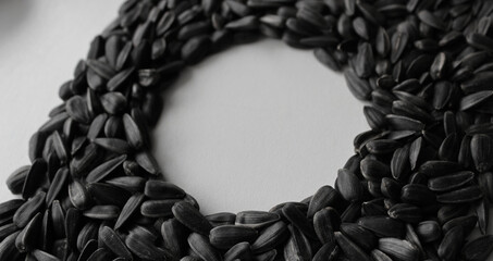 Mark of a round vessel in a dense layer of sunflower seeds on a white surface