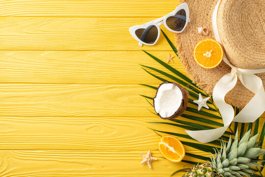 Coastal bliss captured: Top view of sunhat, sunglasses, delicious exotic fruits, island trinkets, palm frond, starfish on sunny wooden surface, offering space for customized text or advertisements