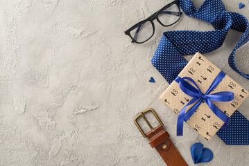 A stylish Fathers day gift arrangement featuring a wrapped present, glasses, a tie, and a leather...