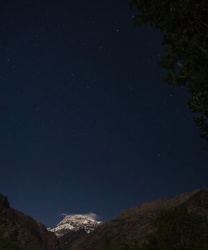 Minimalistic night landscape of the Greater Hansa mountain peak at night against the backdrop of a clear starry sky, a cold mountain with snow and glaciers in the evening