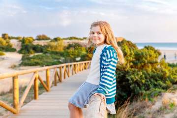 Adorable happy smiling little girl on beach vacation at sunset. Handsome cute preschool child with long blond hairs having fun on family vacations.