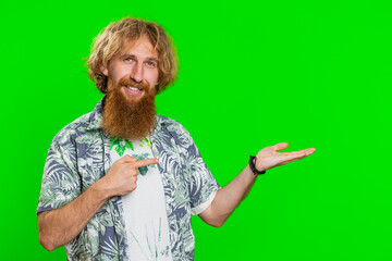 Young bearded man showing thumbs up and pointing right empty place, advertising area for commercial text copy space for goods promotion advertisement. Guy isolated on chroma key background. Lifestyles