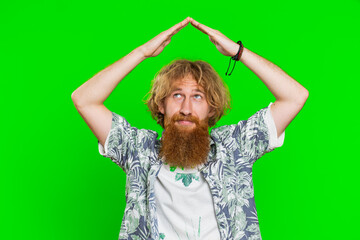 House roof about head. Young bearded man playing childish catching up game, feeling in safe making roof above head with hands, insurance, security service. Guy isolated on green chroma key background