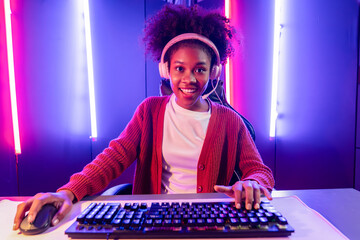 Gaming streamer, African girl playing online fighting with Esport skilled team wearing headphones in neon color lighting room. Talking other players planing strategies to win competitors. Tastemaker.