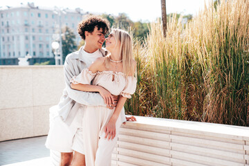 Fototapeta premium Portrait of young smiling beautiful woman and her handsome boyfriend in casual summer clothes. Happy cheerful family. Female having fun. Couple posing in the street background at sunny day