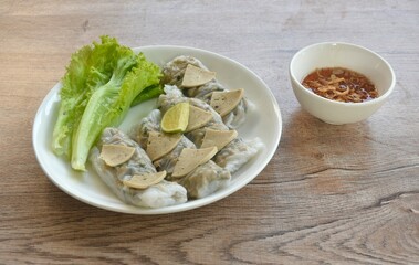 Vietnamese steamed rice dumpling stuffed chop pork and topping slice sausage with fresh green lettuce salad on plate dipping sweet chili sauce dressing crispy fried shallot in cup