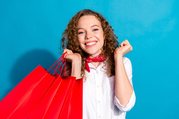 Photo portrait of pretty young woman hold shopping bags raise fists dressed stylish white clothes...