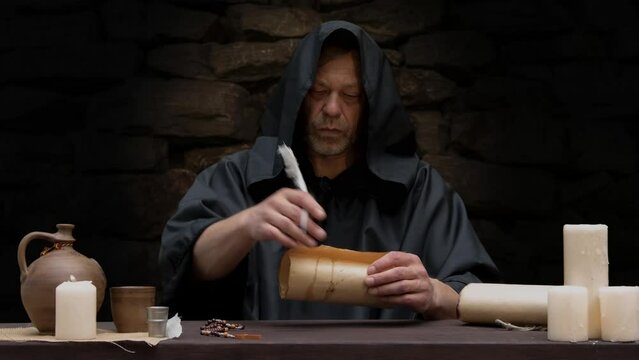 An old monk writes with a quill pen in a scroll 