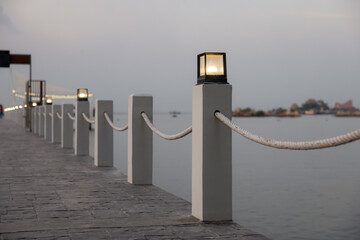 A row of white poles with rope tied to them on a pier