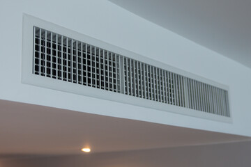 A white vent with black grates is on the ceiling