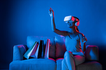 Smart female sit on sofa beside bags wear VR headset connecting metaverse, future cyberspace...