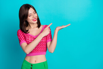 Portrait of cheerful pretty lovely girl wear pink top look indicating at product on hand empty space isolated on blue color background