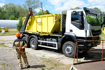 Worker controlling radioactive waste storage container loading on a truck crane