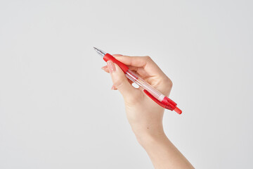 赤いボールペンを持つ女性の手と白い背景