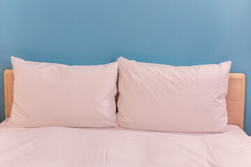 White pillows on a wooden bed with a blue wall as a background.
