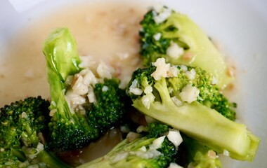 Low fat healthy cuisine. Broccoli stir fried with garlic. Brokoli cah tumis bawang putih. Simple home made food dish isolated on horizontal white plate background.