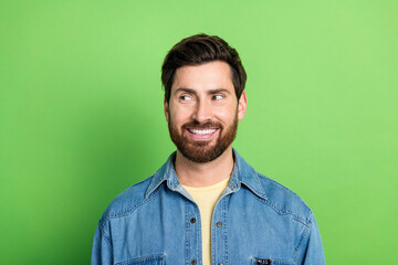 Obraz premium Photo of good mood handsome guy wear denim jacket smiling looking empty space isolated green color background