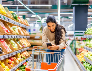 Beautiful young brunette woman looking texting phone app push cart for shopping in shop supermarket 