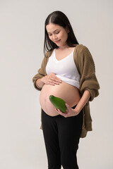 Portrait of Beautiful pregnant woman holding avocado over white background studio, health and maternity concept.