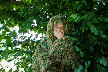 volunteer woman in a camouflage suit made of multi-colored threads, handmade, help to the military, Ukraine
