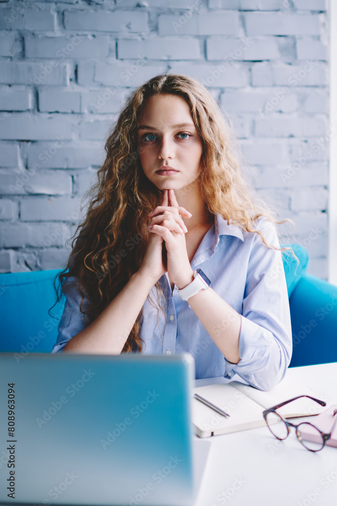 Poster portrait of concentrated female programmer pondering on creating website via laptop device, serious 
