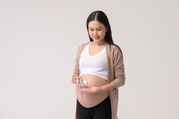 Portrait of Beautiful pregnant woman taking pill and vitamin over white background studio, health and maternity concept